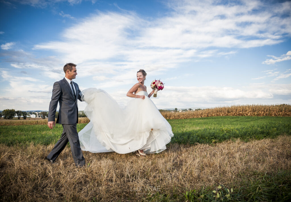 Bride and groom walk in a field after their wedding at Strasburg Inn, photographed by Lux Vitae Photography in Central PA.